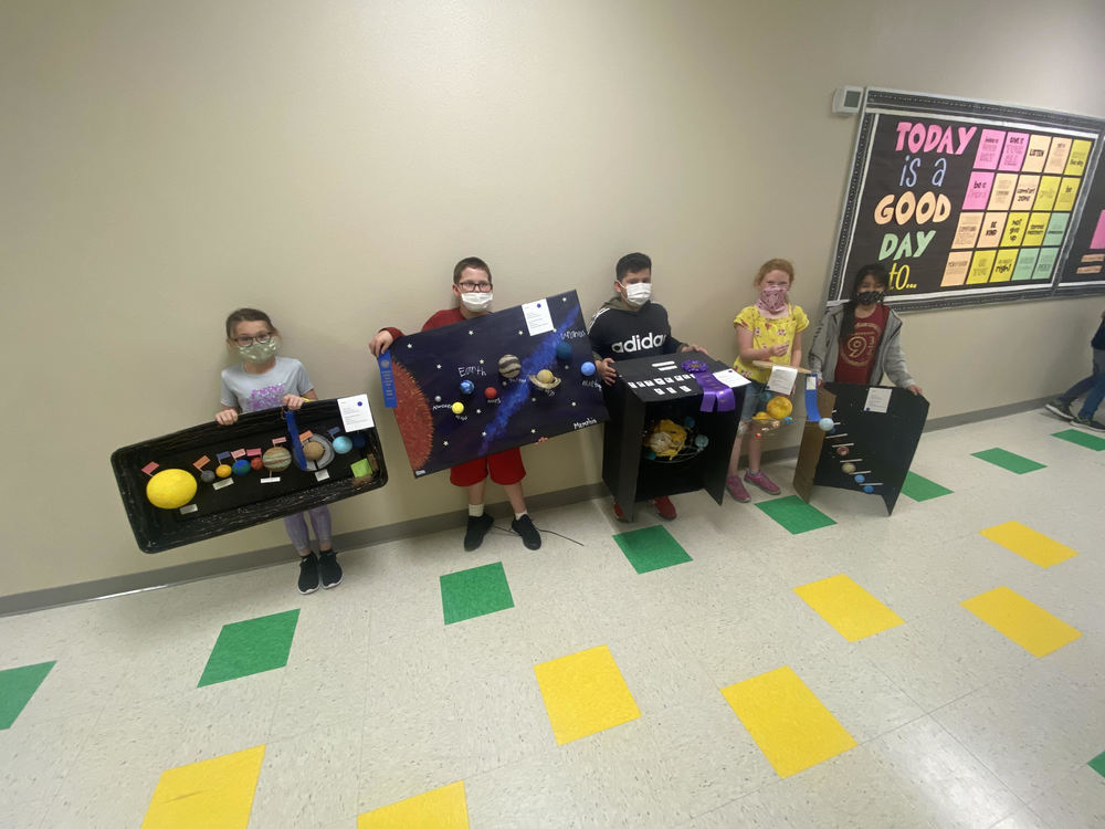 5 students standing in hallway with solar system projects